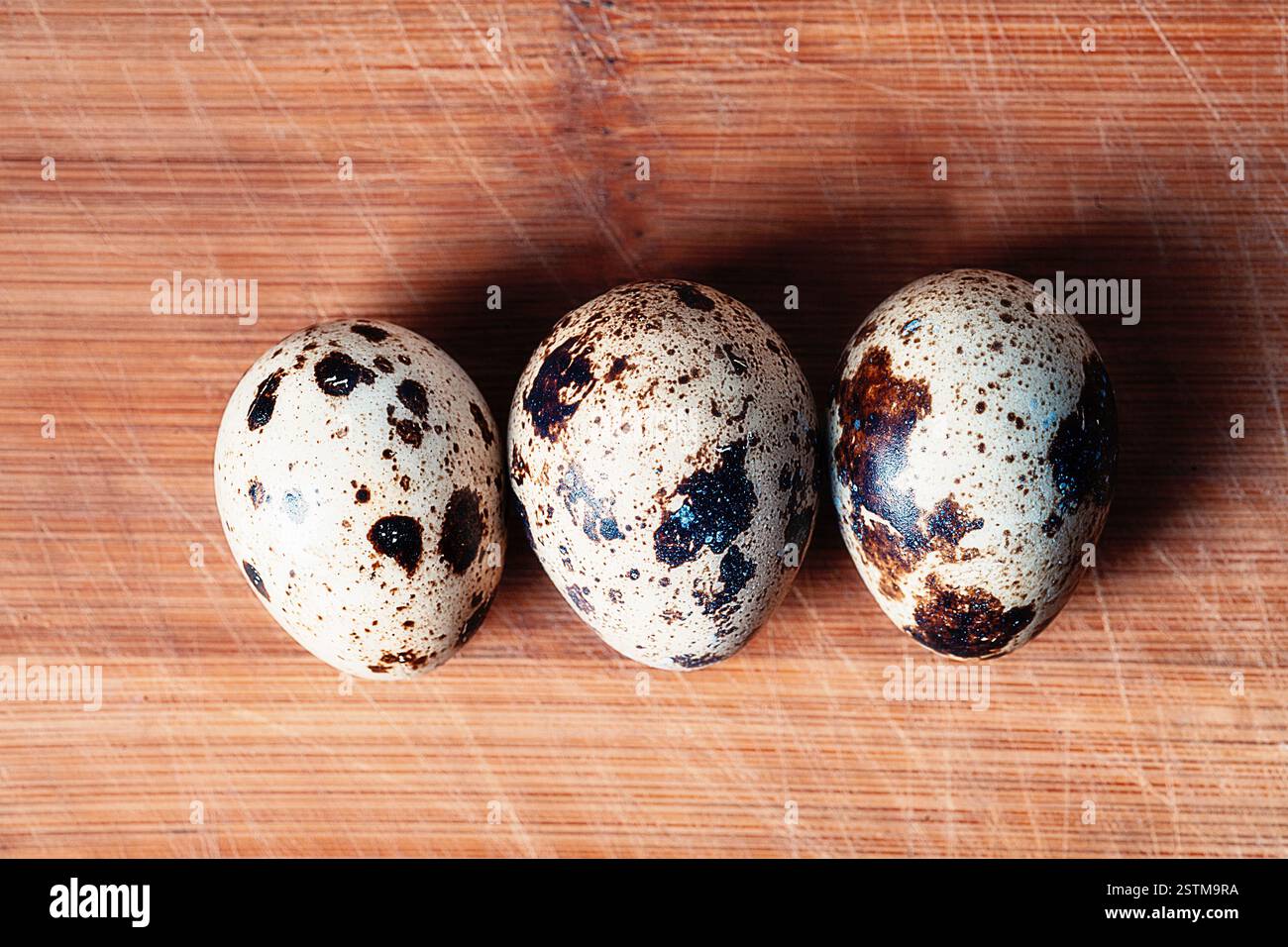 Trois oeufs de caille sur planche de bois vue de dessus, copyspace Banque D'Images