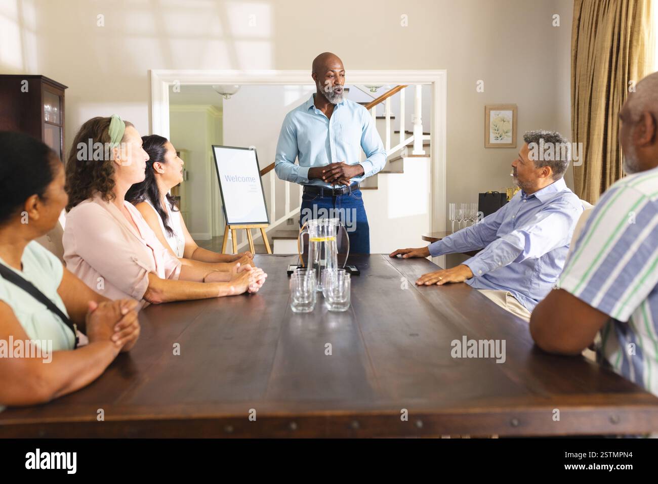 Homme principal dirigeant la réunion avec un groupe diversifié à la maison, discutant des plans. Travail d'équipe, leadership, brainstorming, stratégie, collaboration, réunion d'affaires Banque D'Images