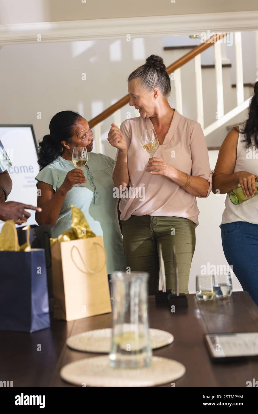 Femmes âgées célébrant avec des verres à vin à la maison, partageant une conversation joyeuse. Célébration, amitié, style de vie, loisirs, à l'intérieur, mature Banque D'Images