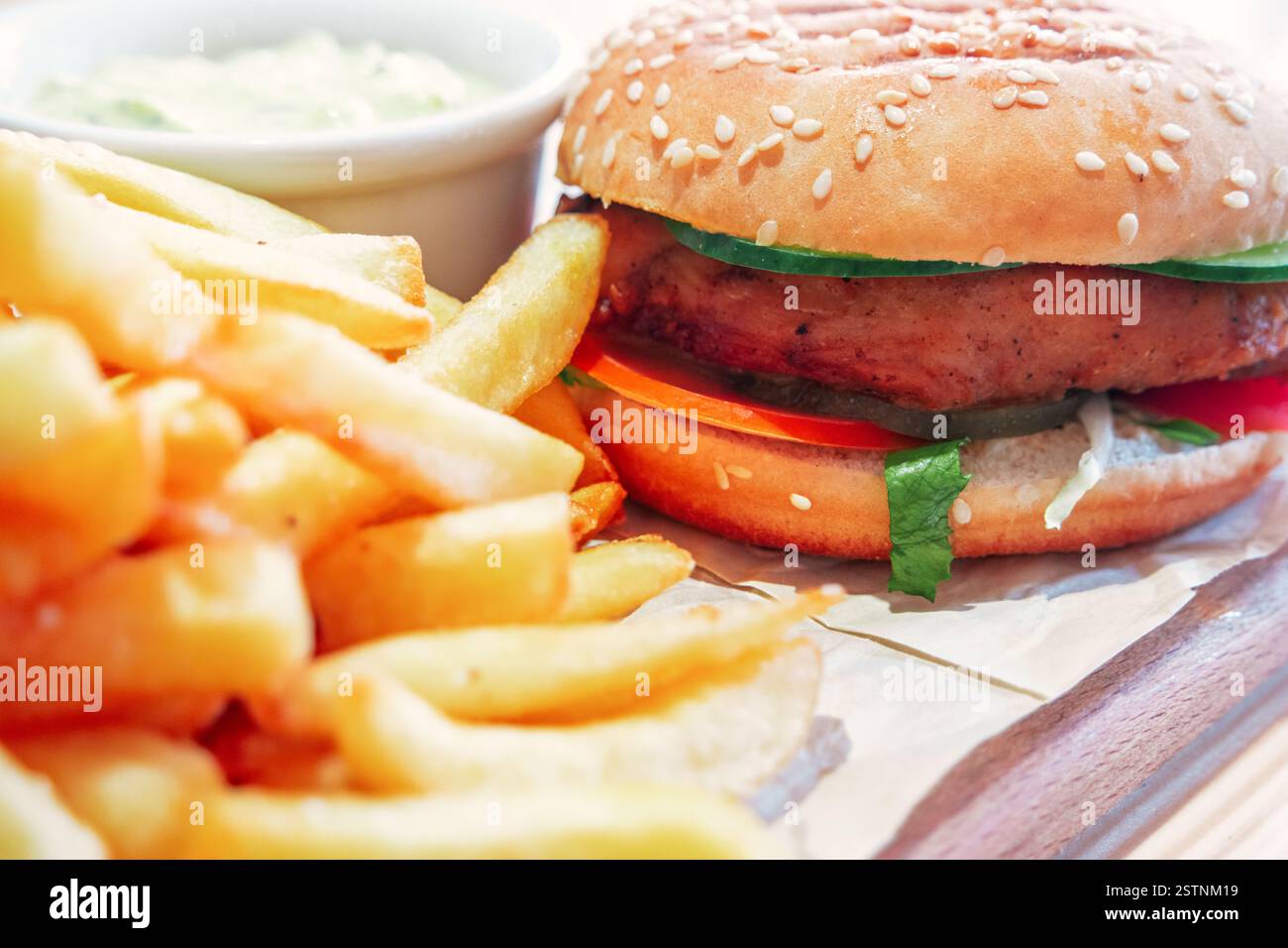 Hamburger grillé sur planche à découper avec fryes français sur fond rustique en bois vue de côté en gros plan. Banque D'Images