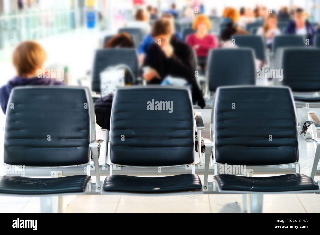Chaises vides dans le salon d'aéroport. Des gens flous qui attendent Banque D'Images