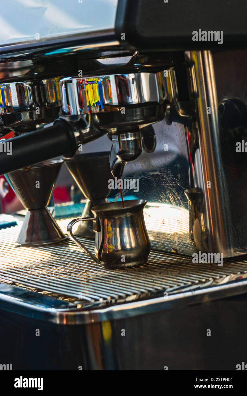 Gros plan d'un espresso qui s'écoule de la machine à café dans un petit bol chromé. Préparation professionnelle du café Banque D'Images