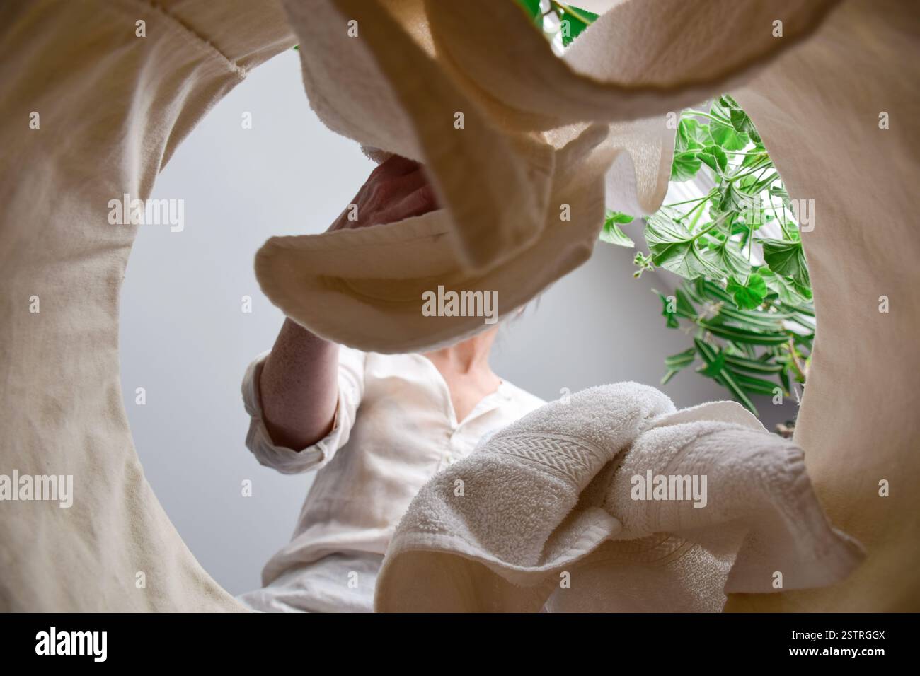 La femme jette des serviettes sales dans le panier à linge, vue de l'intérieur du panier Banque D'Images