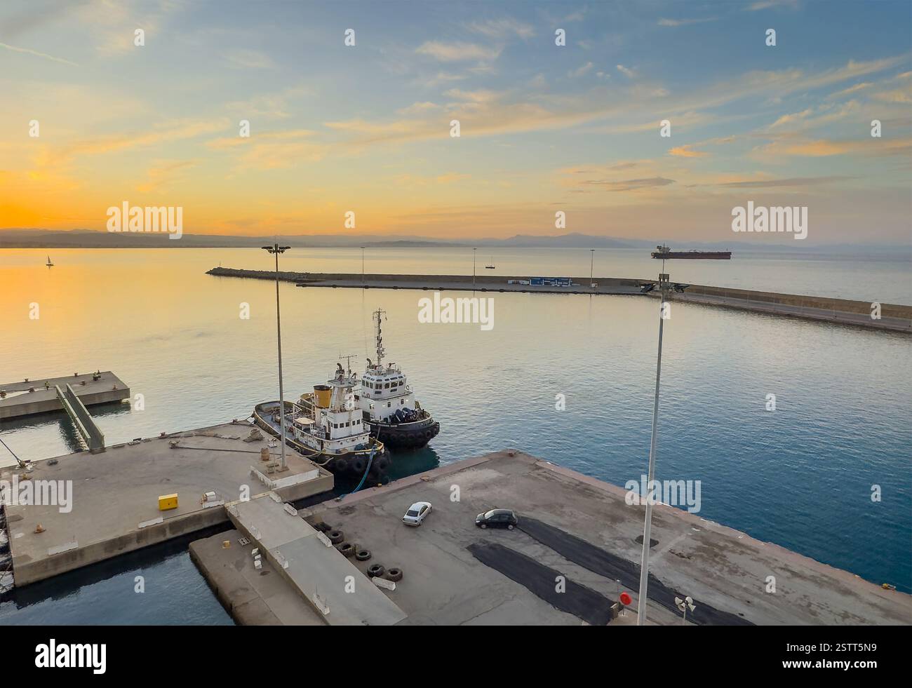Katakolo, Grèce - 4 juillet 2024 : deux remorqueurs au port pendant le lever du soleil colorant le ciel Banque D'Images