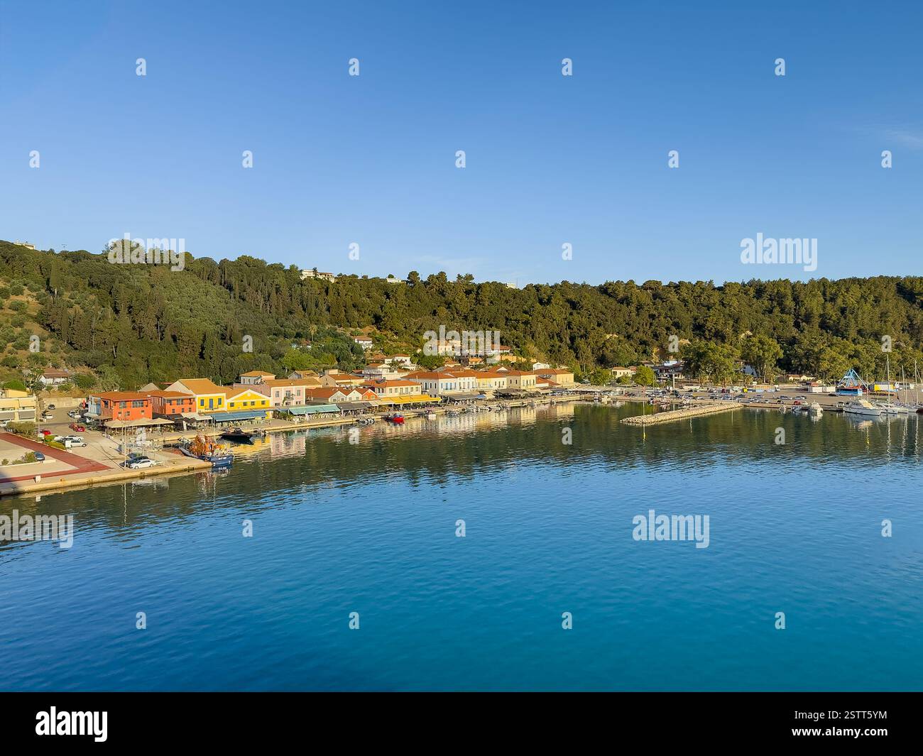 Katakolo, Grèce - 4 juillet 2024 : la promenade au port de plaisance montre une rangée de bâtiments commerciaux principalement des commerces de détail, des restaurants et des bistros. Boisé Banque D'Images