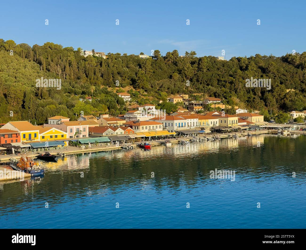 Katakolo, Grèce - 4 juillet 2024 : la promenade au port de plaisance montre une rangée de bâtiments commerciaux principalement des commerces de détail, des restaurants et des bistros. Boisé Banque D'Images