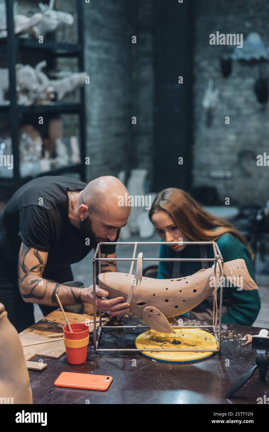 Les gens travaillent soigneusement sur la baleine d'argile dans l'atelier Banque D'Images