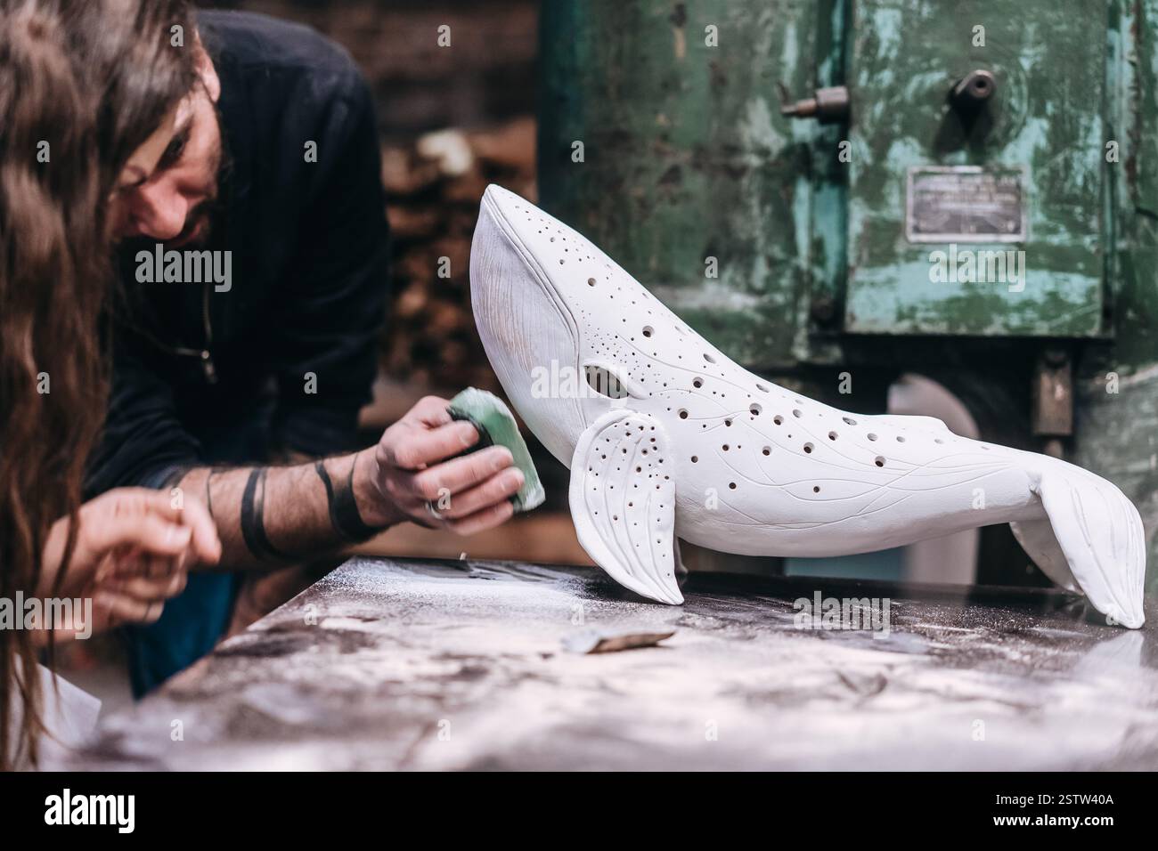 Les gens travaillent avec soin sur une baleine en céramique en atelier Banque D'Images