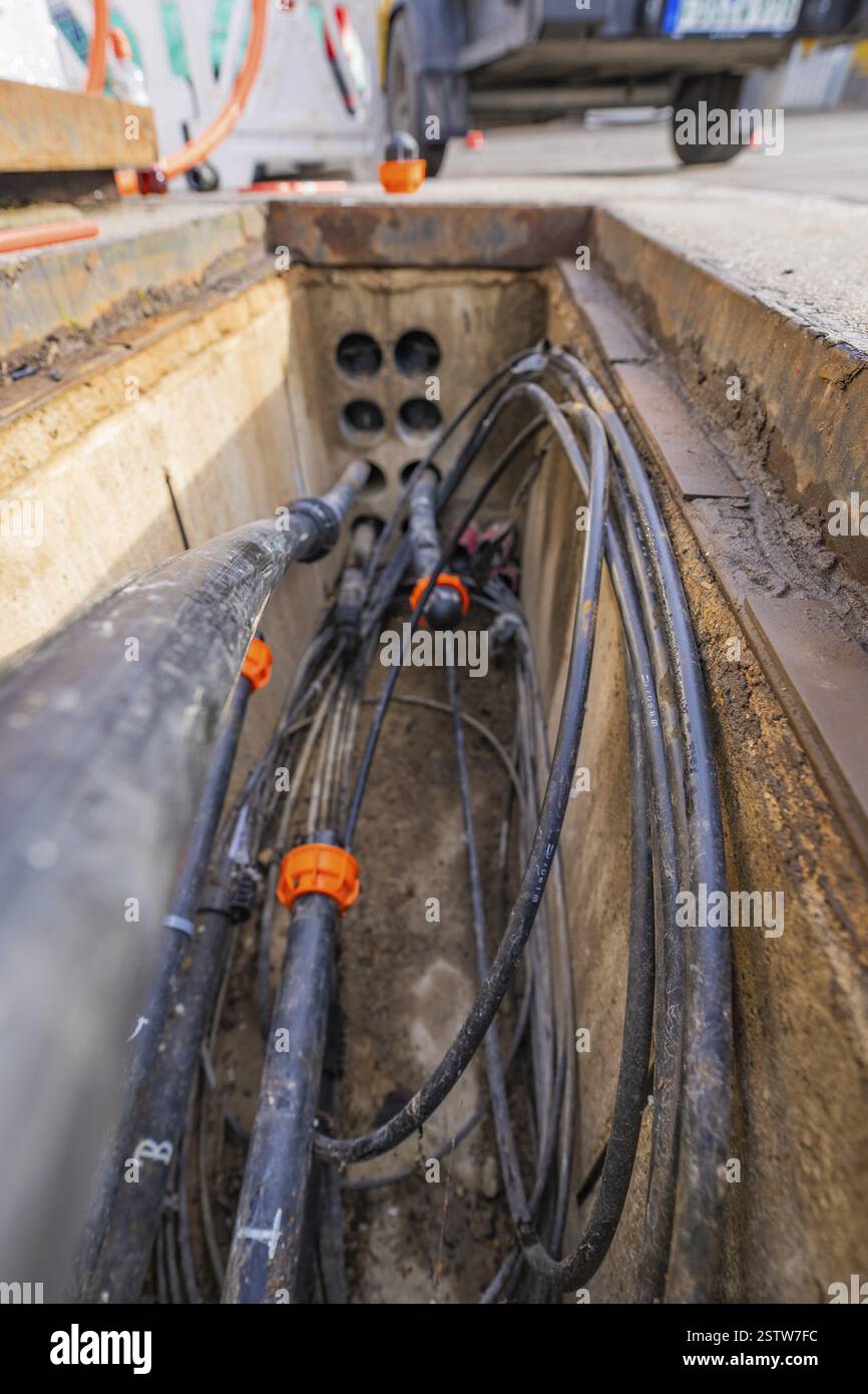 Vue dans un puits ouvert avec des câbles et des tuyaux sur un chantier de construction, Wend Glasfasermontage lors de l'installation de conduits pour câbles à fibres optiques Banque D'Images