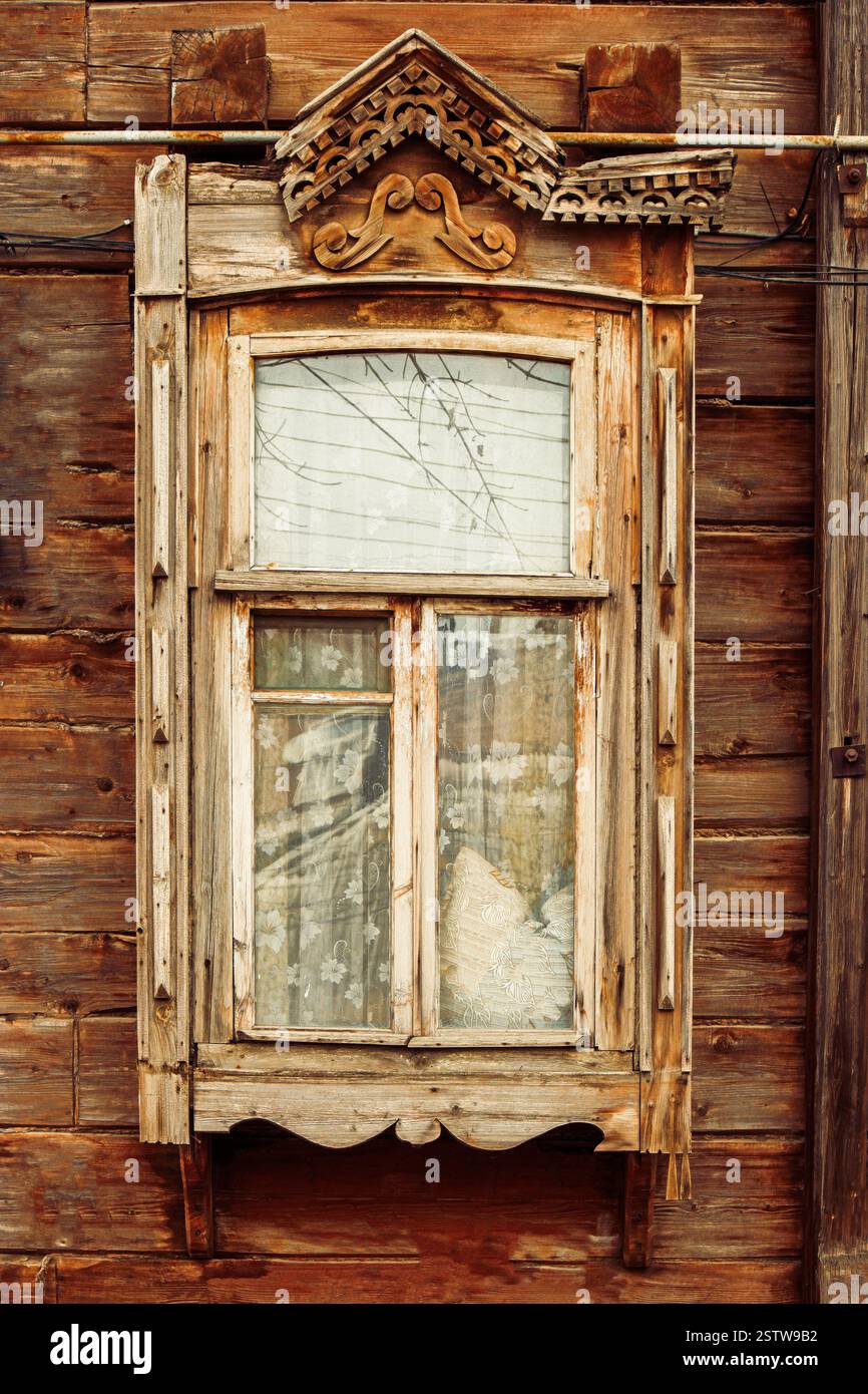 Gros plan de la fenêtre en bois dans la maison de campagne russe avec des décorations à moitié cassées Banque D'Images