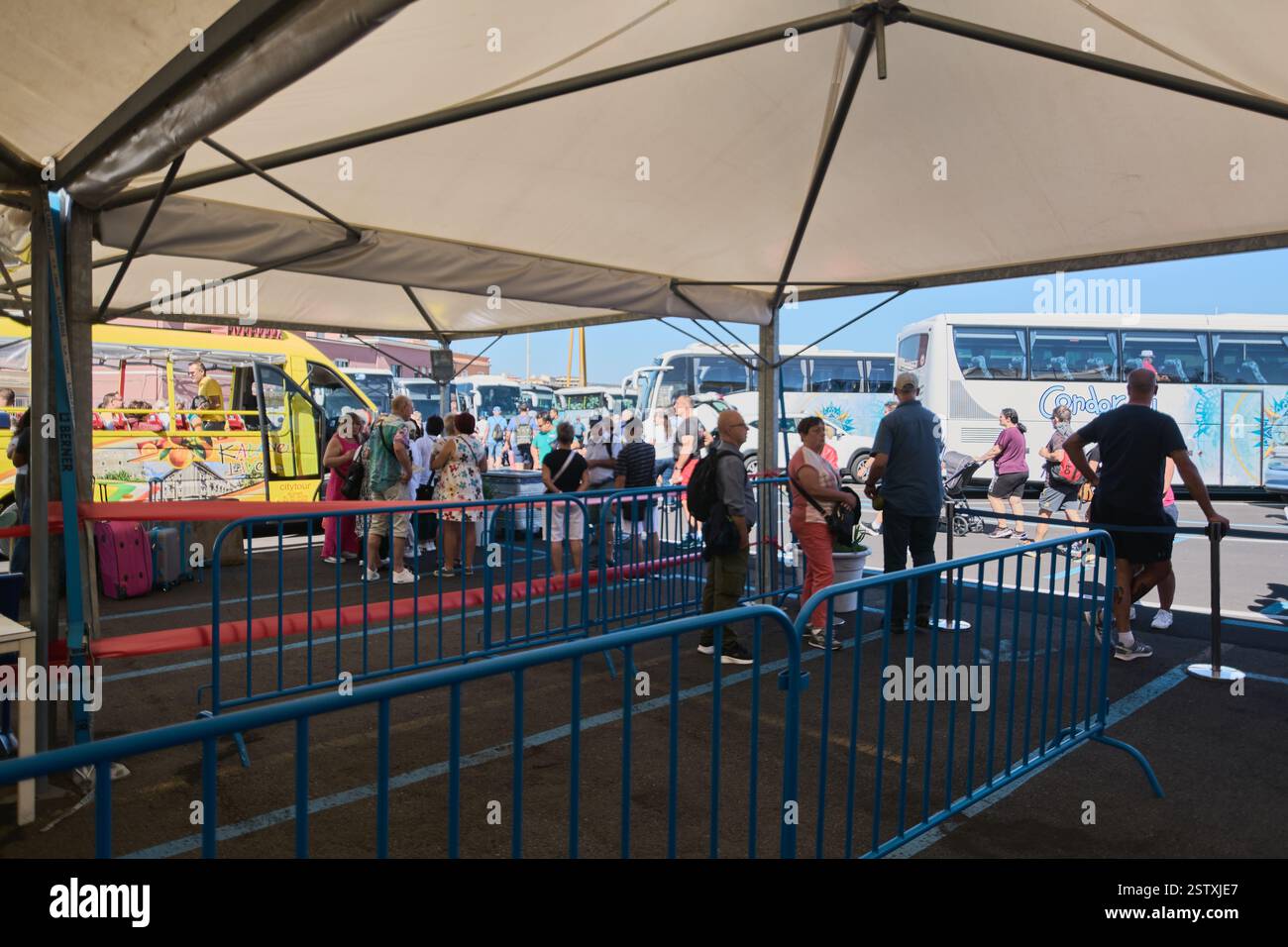 Catane, Italie, 20 février 2025 : bus touristiques avec des gens faisant la queue sous une tente. Plusieurs bus sont prêts à partir, avec des passagers chargeant des bagages Banque D'Images