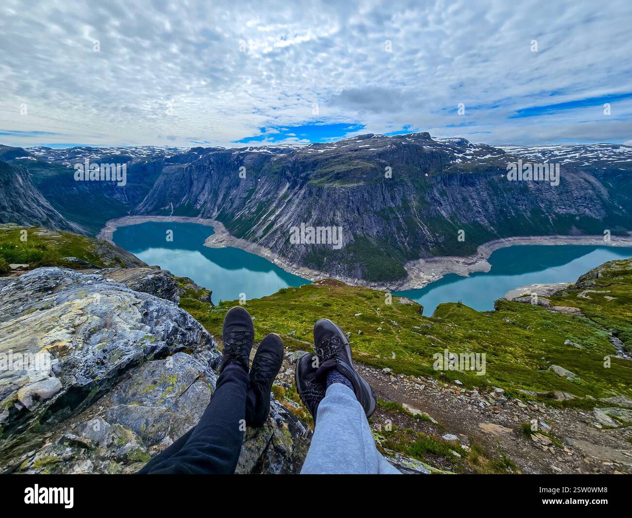 Vue sur les fjords en Norvège au lever du soleil avec les pieds des randonneurs au premier plan, Trolltunga, Norvège Banque D'Images