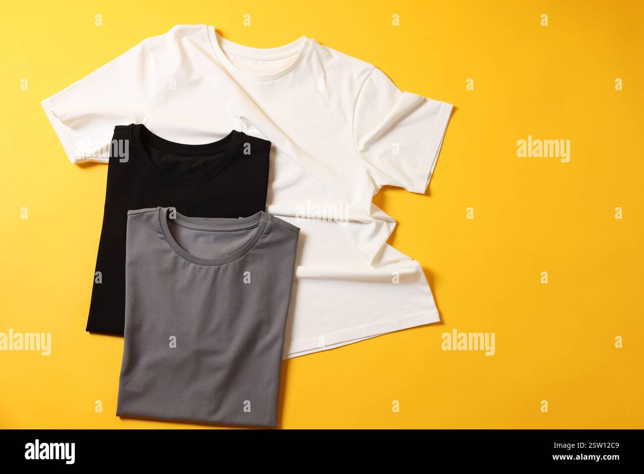 T-shirts vierges sur fond jaune, pose à plat. Maquette pour le design Banque D'Images T-shirts vierges sur fond jaune, pose à plat. Maquette pour le design Banque D'Images