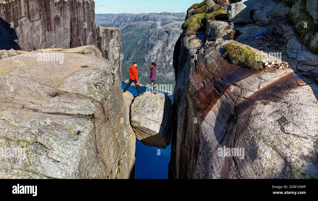 Les amateurs d'aventure traversent le Precipice à Kjeragbolten dans Norways Majestic Landscape Banque D'Images