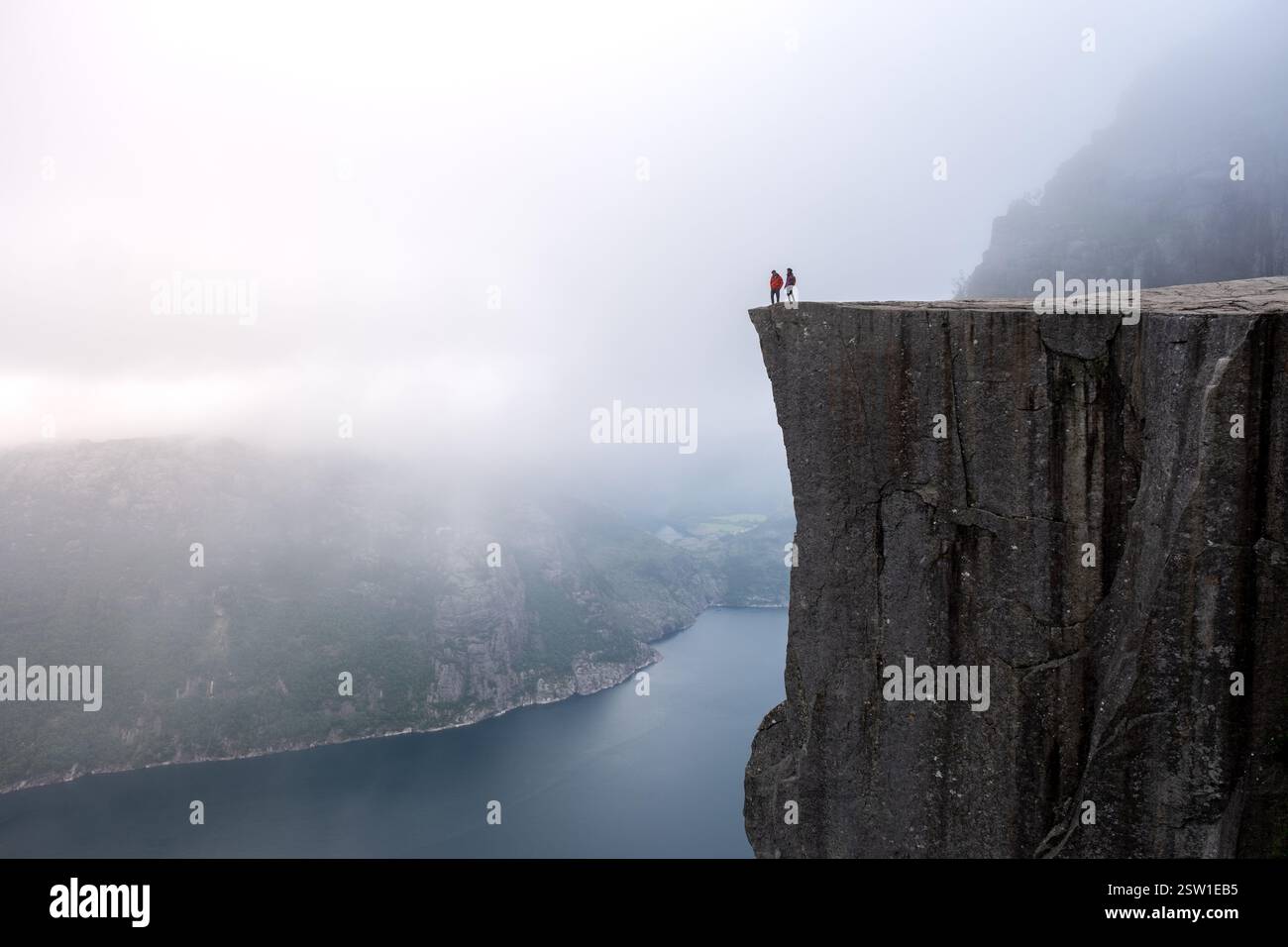 Randonneurs aventureux debout sur la falaise Preikestolen surplombant le fjord en Norvège à Dawn Banque D'Images