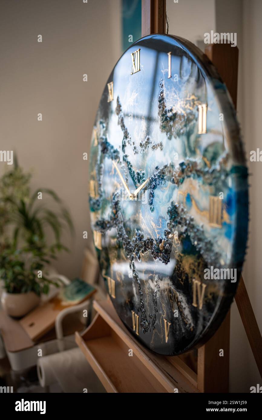 Élégante grande horloge murale en résine époxy faite dans des tons bleus, dorés, bruns avec des motifs nautiques Banque D'Images