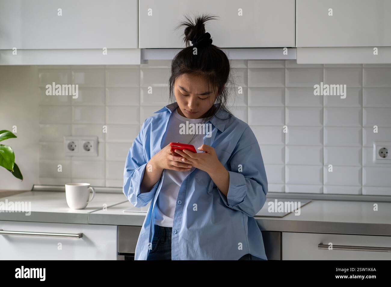 Réfléchir à une femme asiatique qui frognait le visage en tenant un téléphone portable recevoir un message de mauvaises nouvelles, au sujet du licenciement Banque D'Images