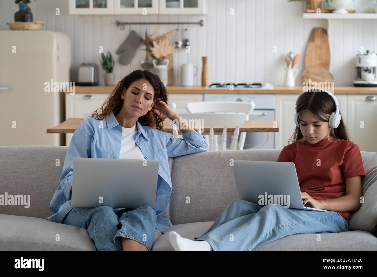 Famille moderne mère et fille assis sur le canapé à la maison utiliser des appareils numériques portables pour le travail et l'étude Banque D'Images