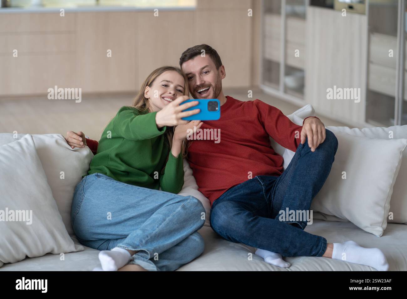 Heureux couple aimant repos regarder l'écran du téléphone faire selfie, appeler à des amis utiliser l'appel vidéo à la maison Banque D'Images