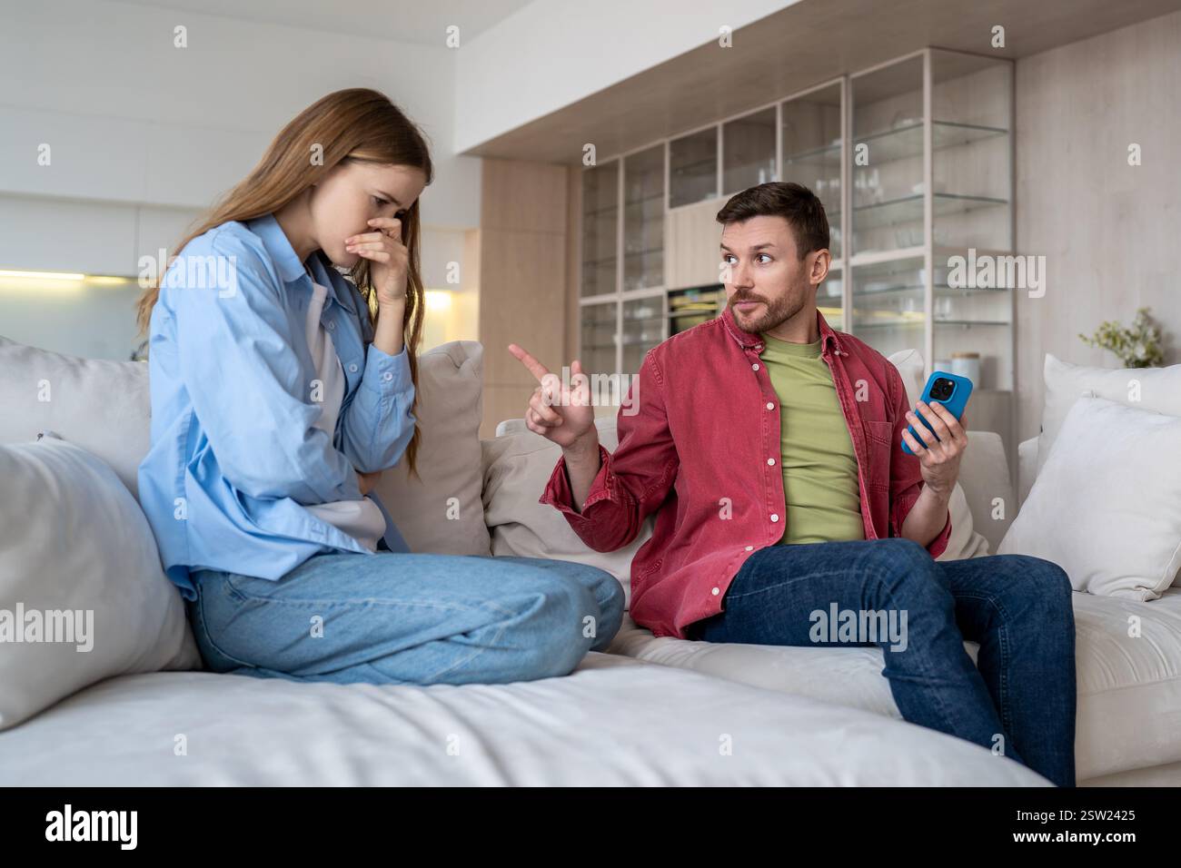 Femme bouleversée, homme sérieux querelle sur le bavardage ambigu, SMS sur les applications de rencontres, tricherie. Banque D'Images