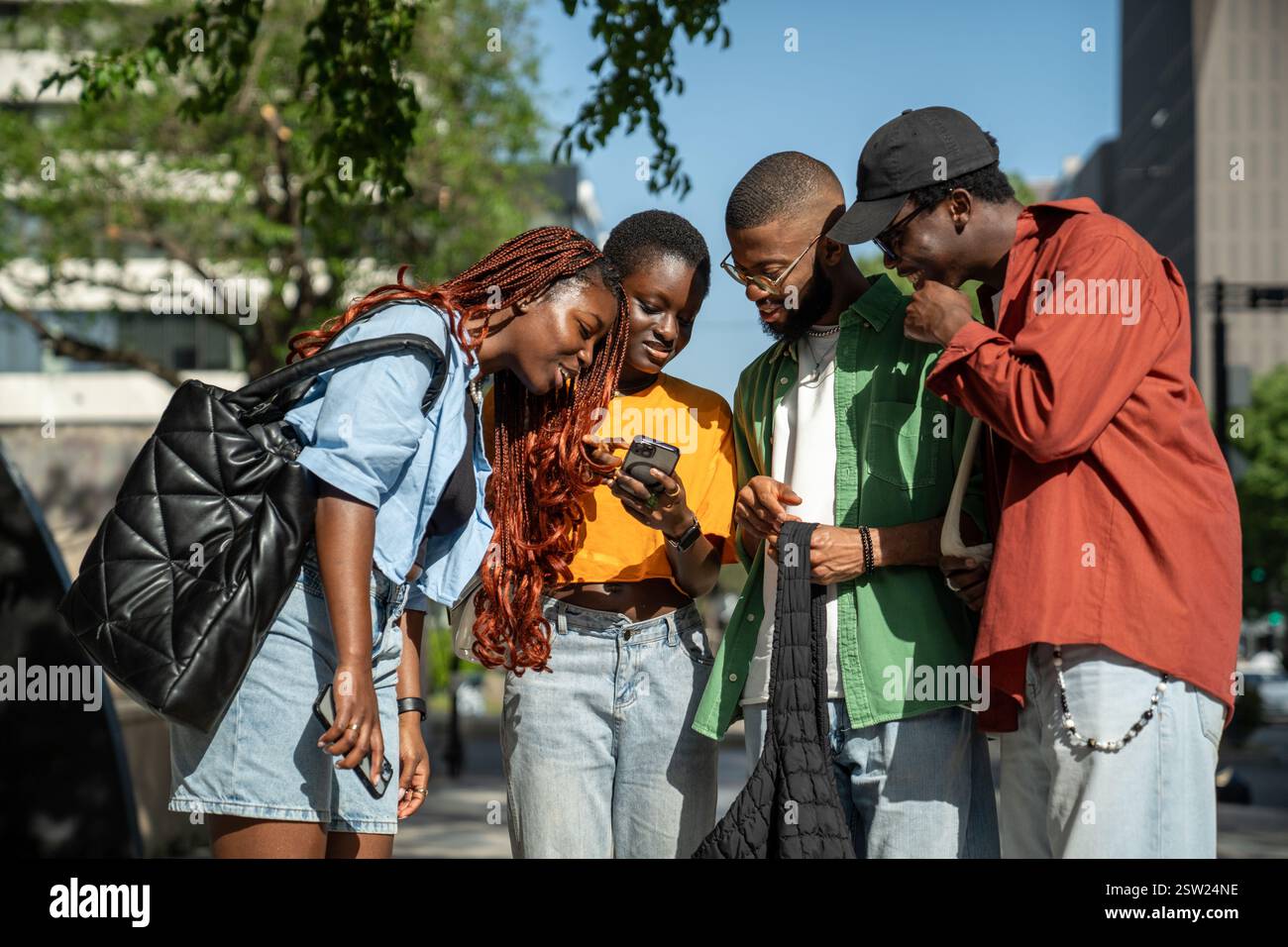 Compagnie souriant amis noirs dehors avec la blogueuse fille tenant le téléphone montrant le profil des médias sociaux. Banque D'Images