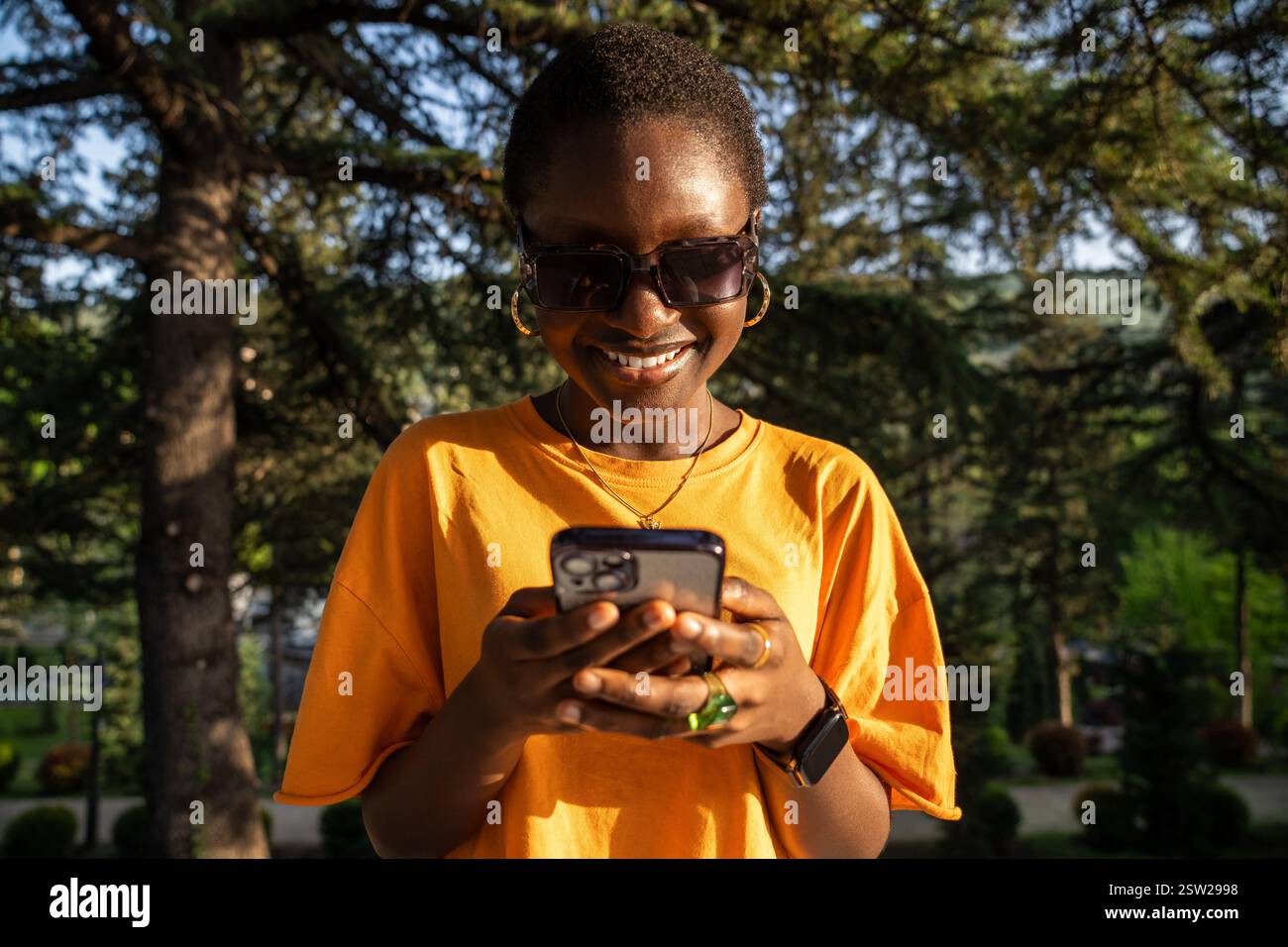 Rire femme afro-américaine à l'aide du téléphone, heureux sourire tout en regardant l'écran du smartphone. Banque D'Images