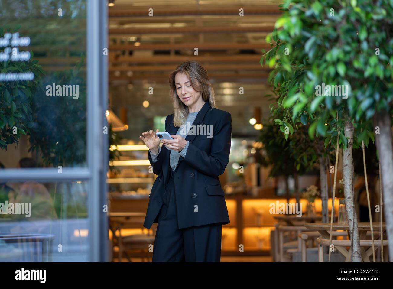 Femme d'affaires discutant sur Internet sur smartphone, gère les contrats et la correspondance dans le couloir Banque D'Images