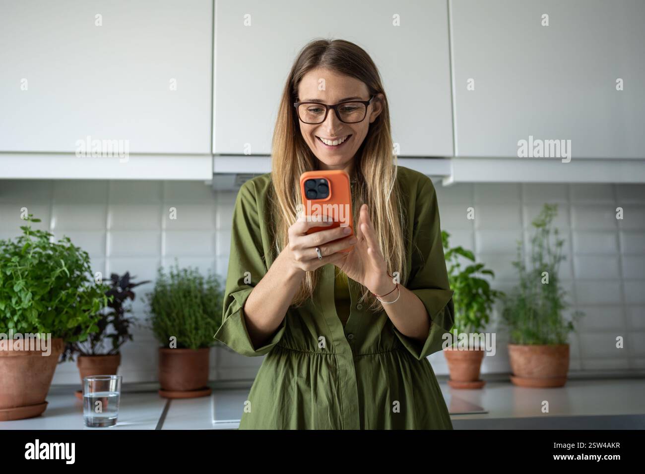 Heureuse femme scandinave millénaire lisant le message dans le téléphone portable souriant profiter de la communication à la maison Banque D'Images