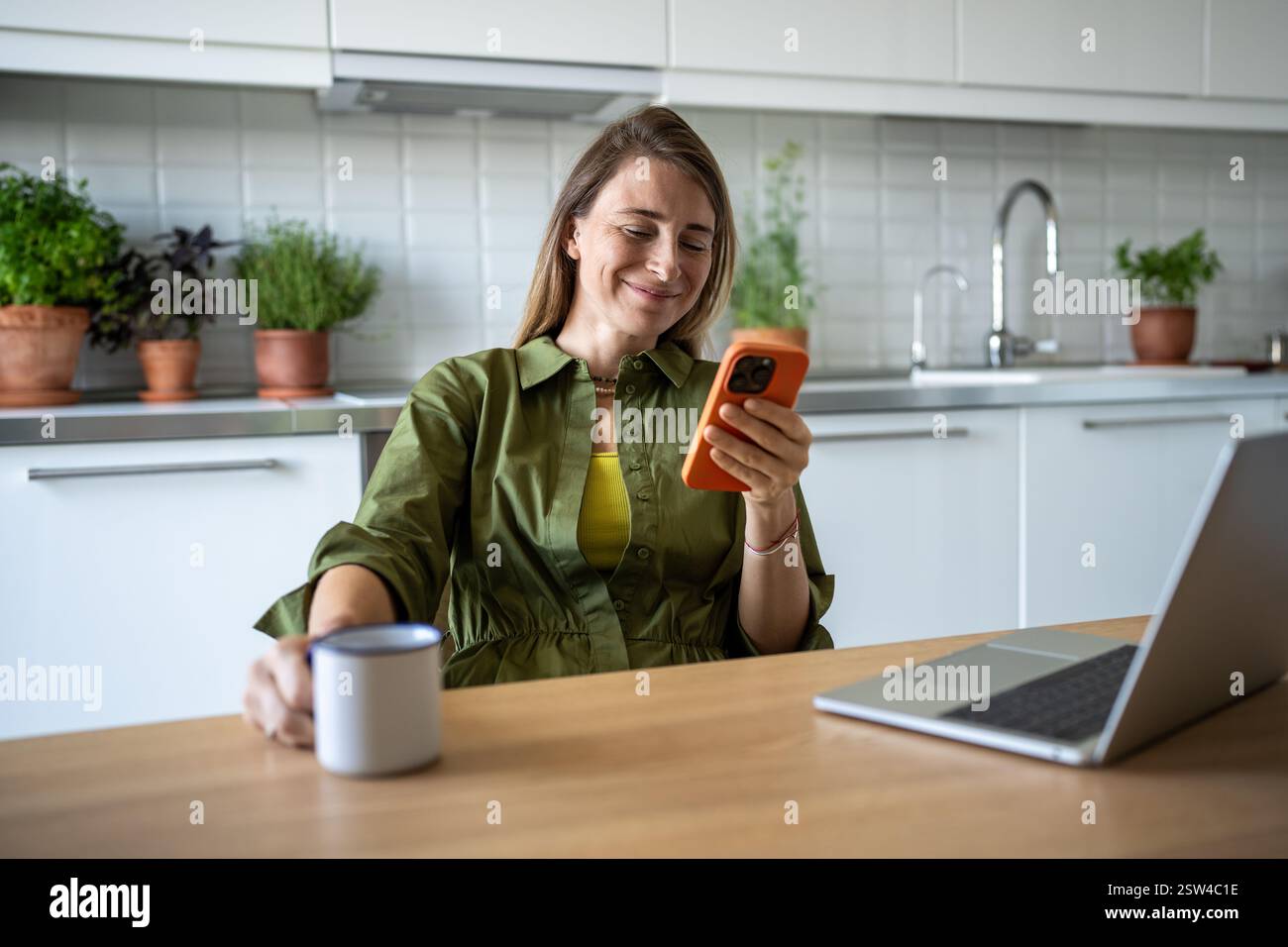 Souriante femme heureuse freelance travaillant procrastinant prendre pause, surfer sur le web dans le téléphone mobile. Banque D'Images