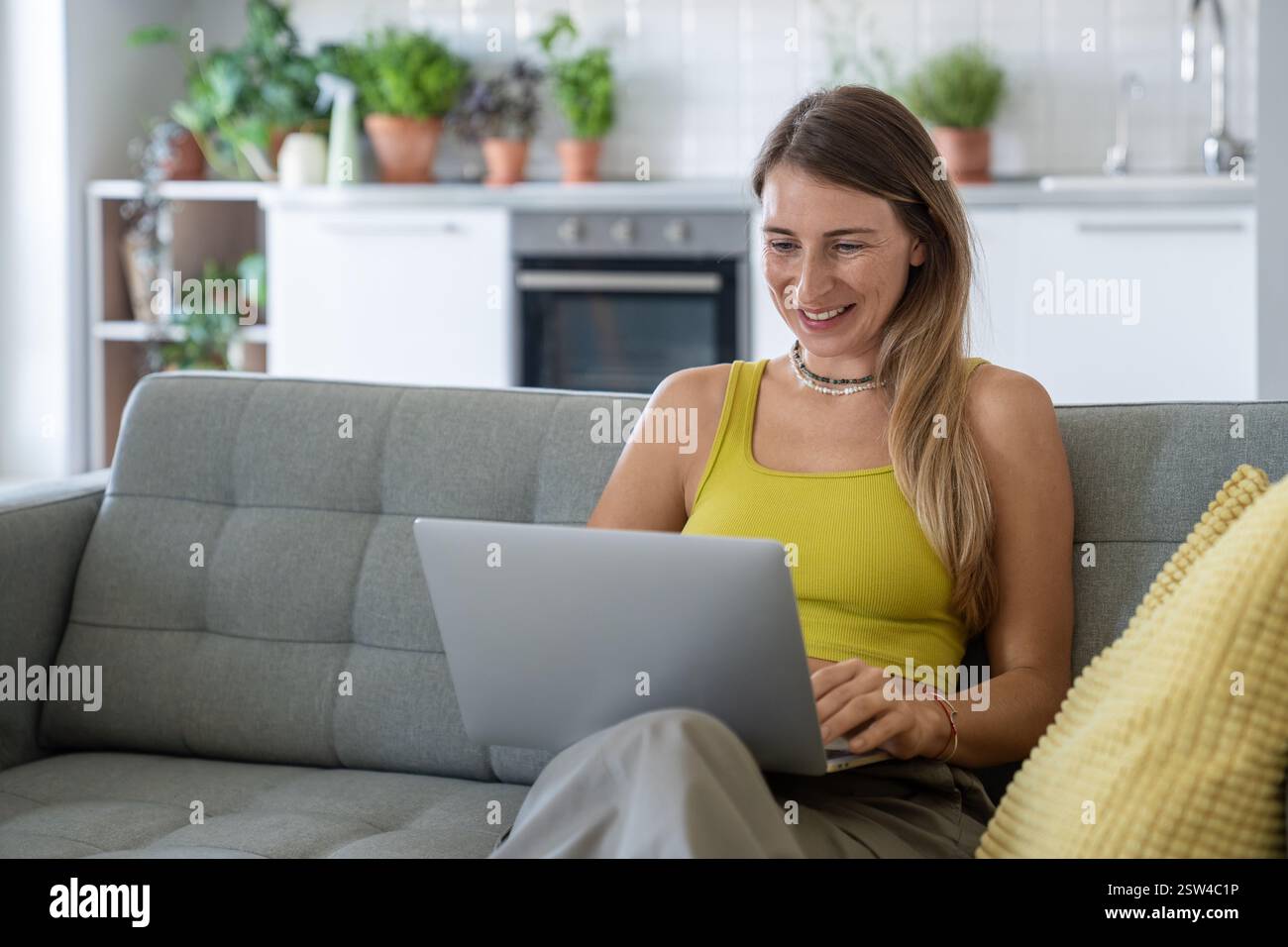 Femme joyeuse assis sur le canapé à la maison avec ordinateur portable souriant regardant l'écran recevoir de bonnes nouvelles dans le message. Banque D'Images
