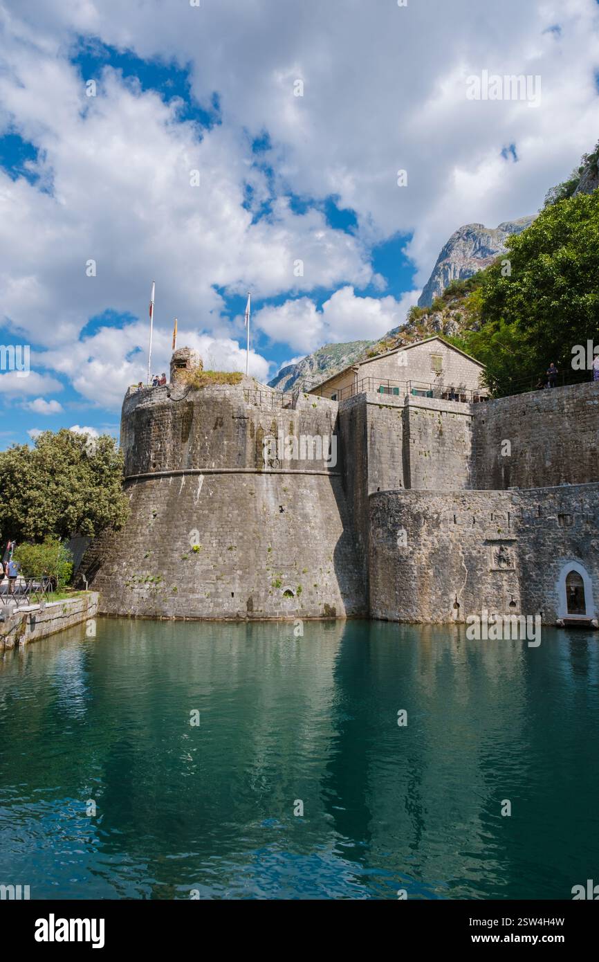 Découvrez les anciennes fortifications de Kotor par le front de mer serein et le ciel bleu clair Banque D'Images