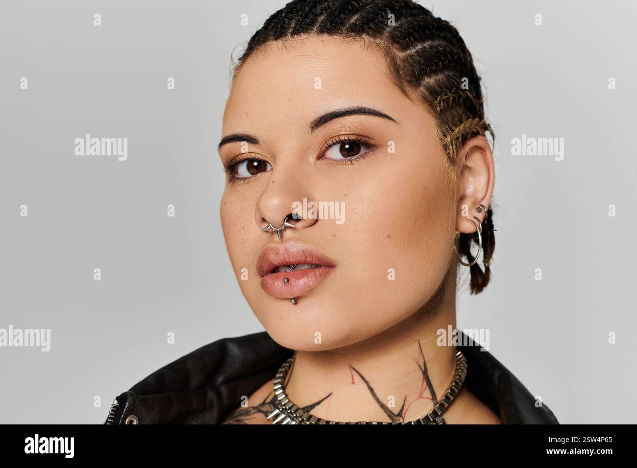 Une jeune femme aux cheveux tressés et aux piercings distinctifs respire la confiance dans ses choix de mode. Banque D'Images