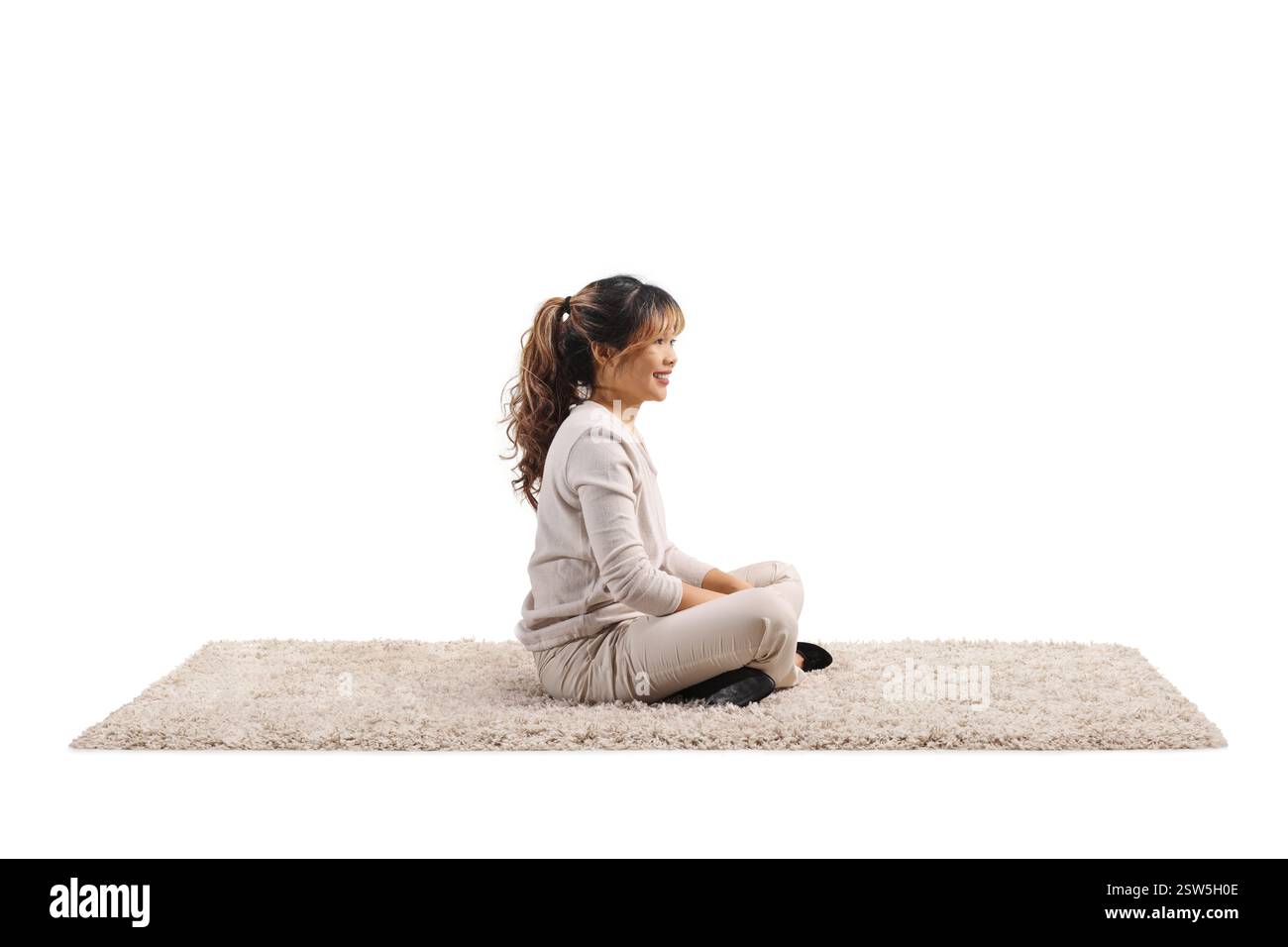 Jeune femme asiatique assise sur un tapis avec des jambes croisées isolé sur fond blanc Banque D'Images