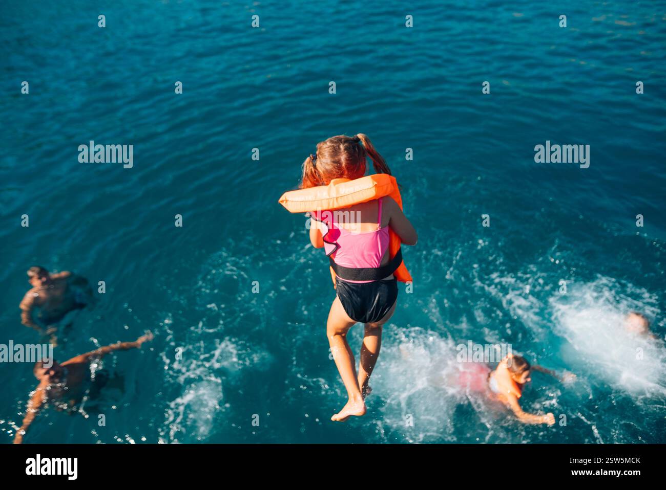 Joyeux Summer Fun enfants jouant joyeusement dans l'océan avec des gilets de vie aux couleurs vives Banque D'Images