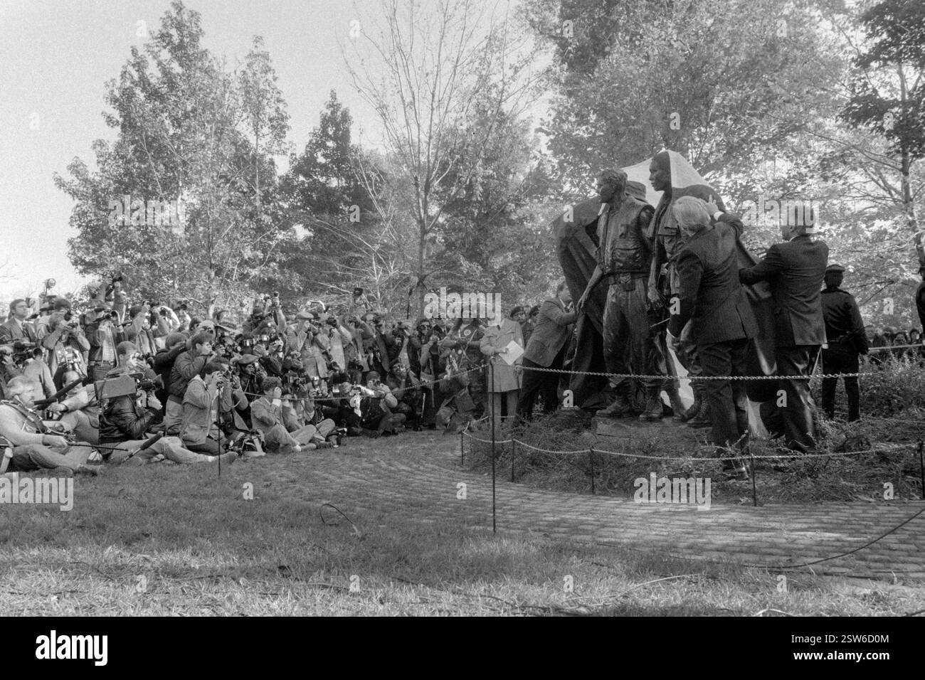 Les officiels lèvent la couverture de la statue des « trois combattants » du Vietnam Memorial lors de la cérémonie de dévoilement, le 9 novembre 1984 à Washington, D.C. de gauche à droite : Jan Scruggs, Vietnam Veterans Memorial Fund, Sen. John Warner, et l’artiste de casting Joel Meisner. Banque D'Images