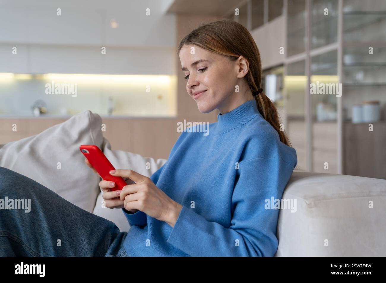 Heureuse femme détendue souriante en utilisant le chat téléphonique dans les médias sociaux, les achats en ligne assis à la maison. Banque D'Images
