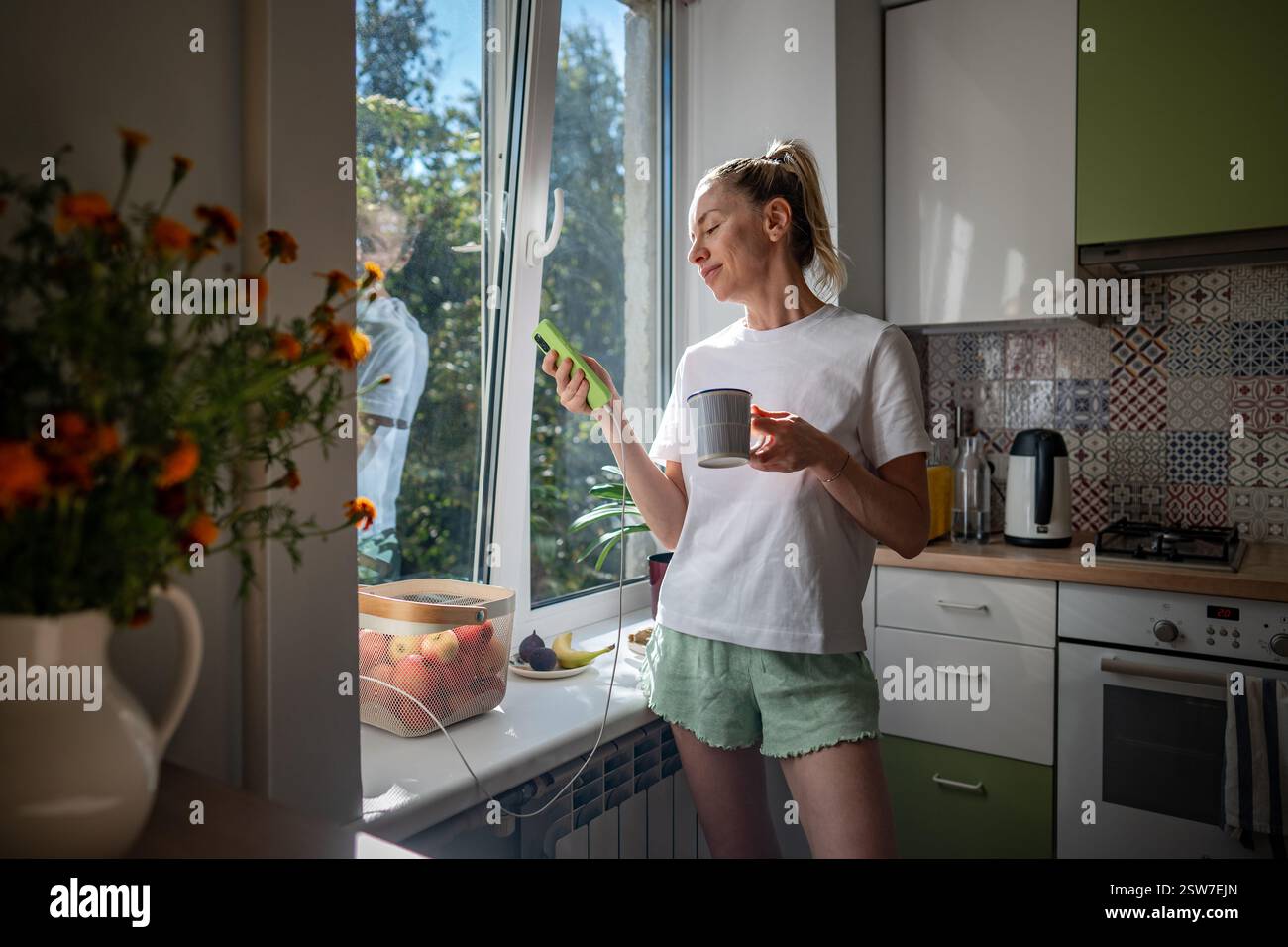 Matin paresseux, procrastination avec téléphone de femme buvant du café en pyjama défilant des toiles sur téléphone Banque D'Images