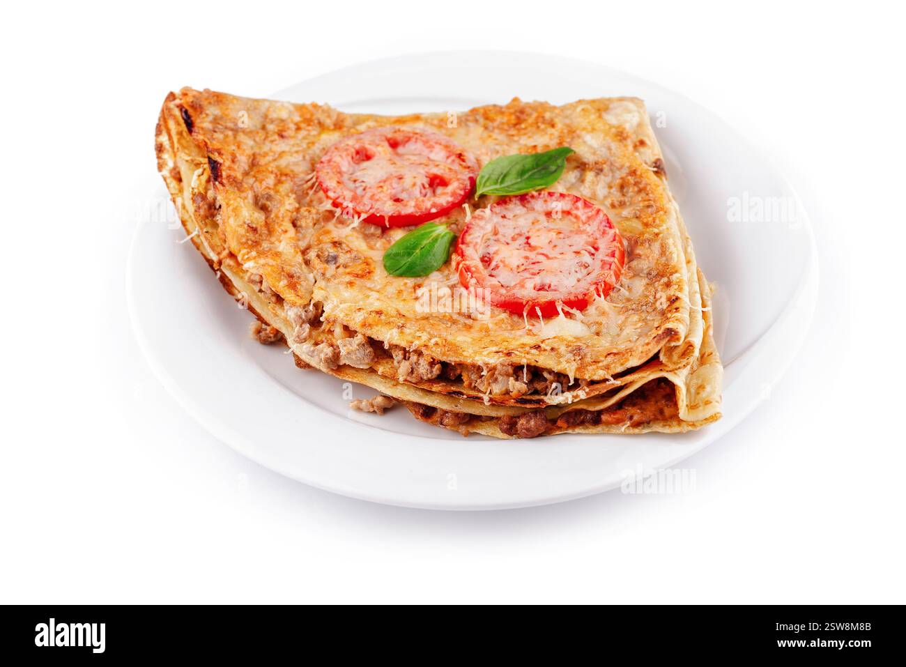 Délicieuses crêpes avec de la viande, des tomates et du fromage formant un triangle sur une assiette blanche Banque D'Images