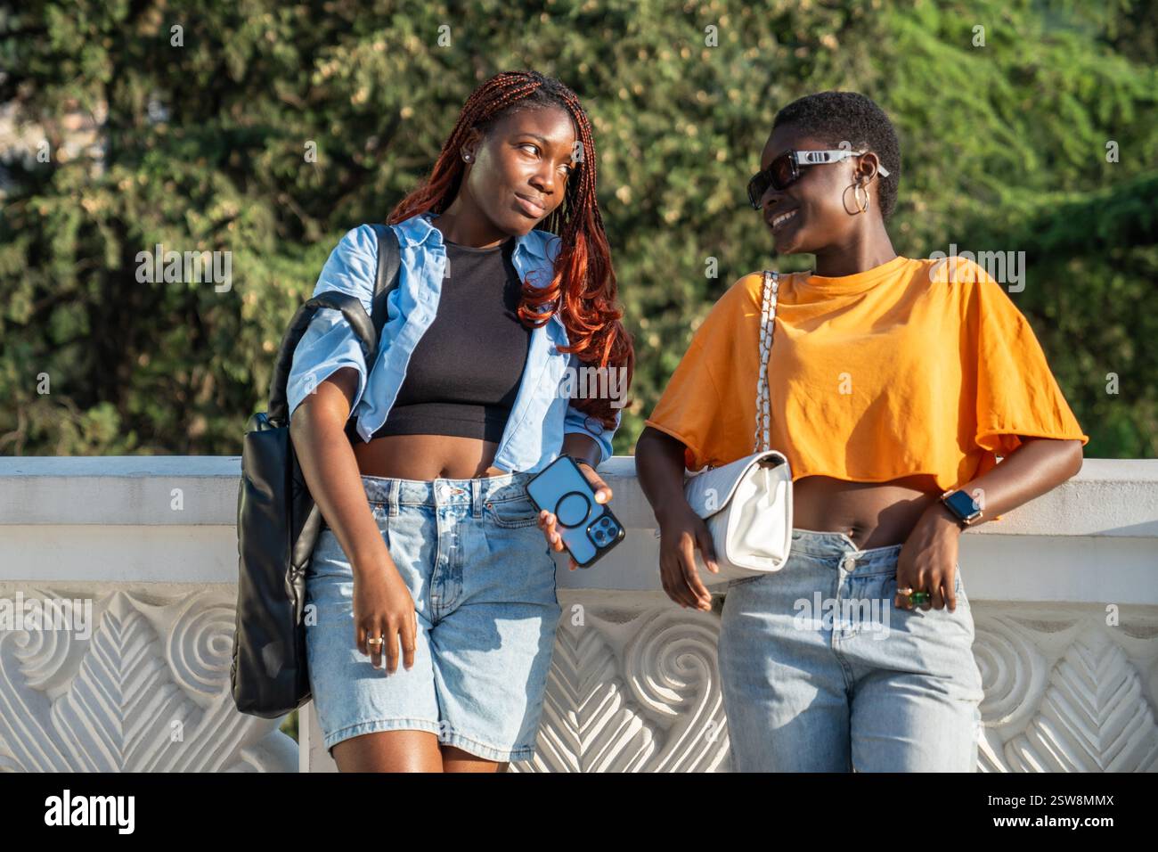 Souriantes étudiantes noires détendues sur Together Walk in City. Girl Fun regarde rire ami. Banque D'Images