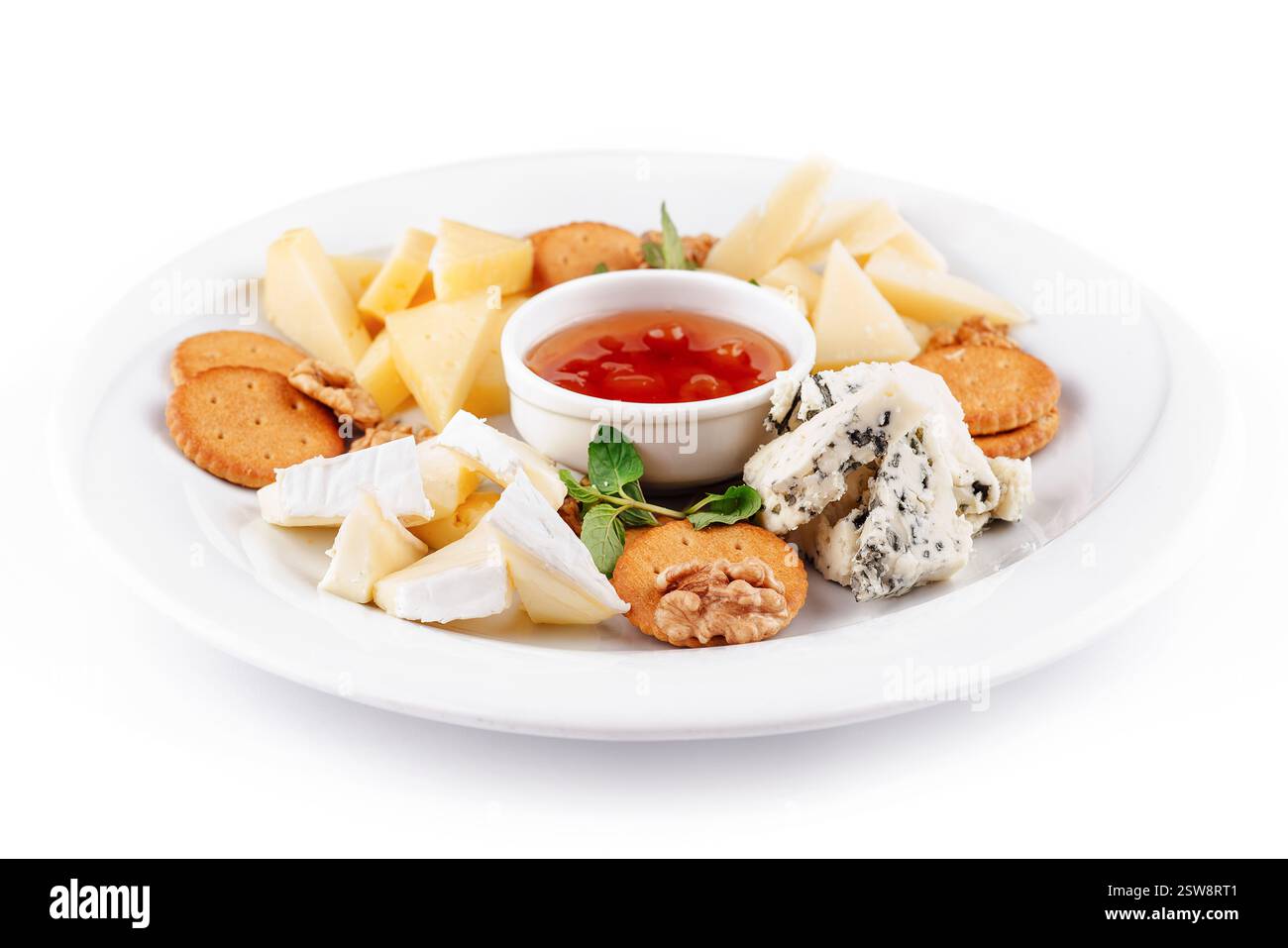 Délicieuse assiette de fromage présentant une variété de fromages, de noix et de sauce Banque D'Images