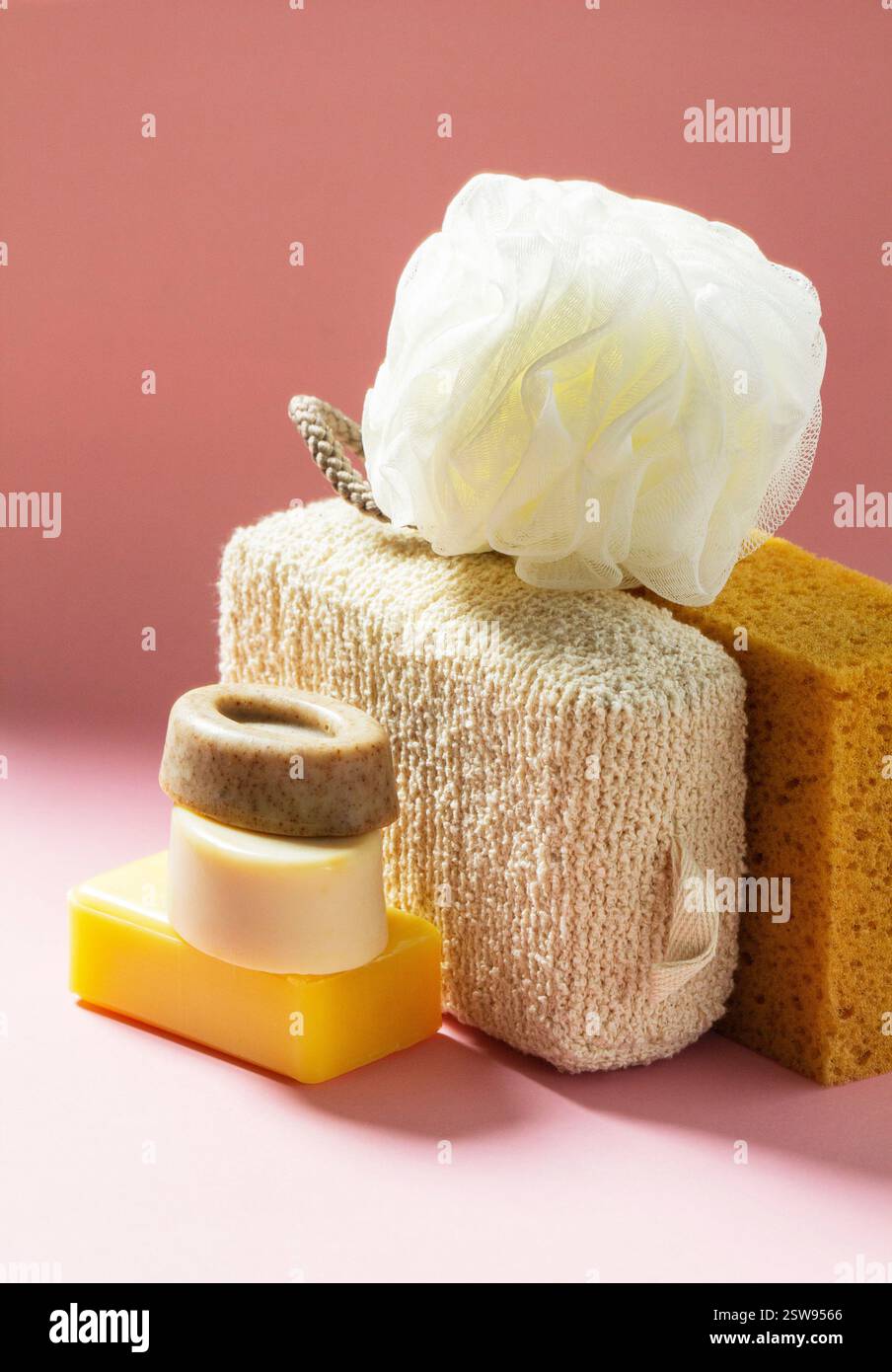 Ensemble d'accessoires de bain, éponges de différentes tailles et formes et savon fait à la main sur un fond rose. Kit individuel pour le soin de la peau du corps. Banque D'Images