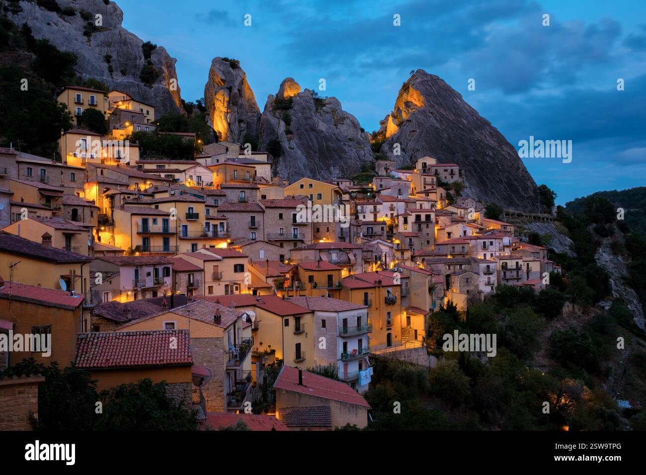 Alors que le crépuscule s'installe sur Castelmezzano, les lumières du village scintillent sur fond de falaises imposantes Banque D'Images