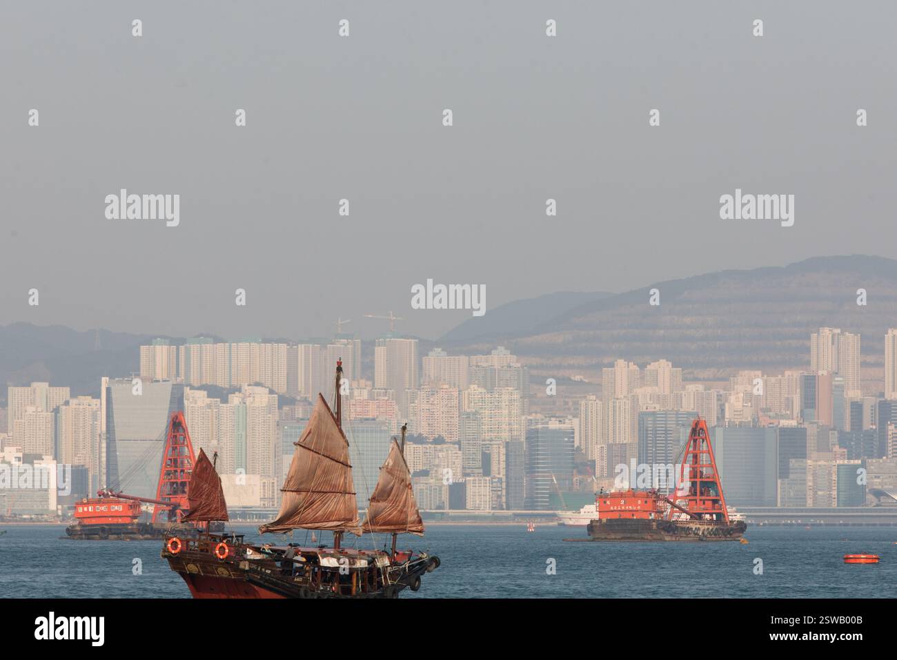 La jonque chinoise traditionnelle passe devant les gratte-ciel de Hong Kong, Victoria Harbour. Banque D'Images