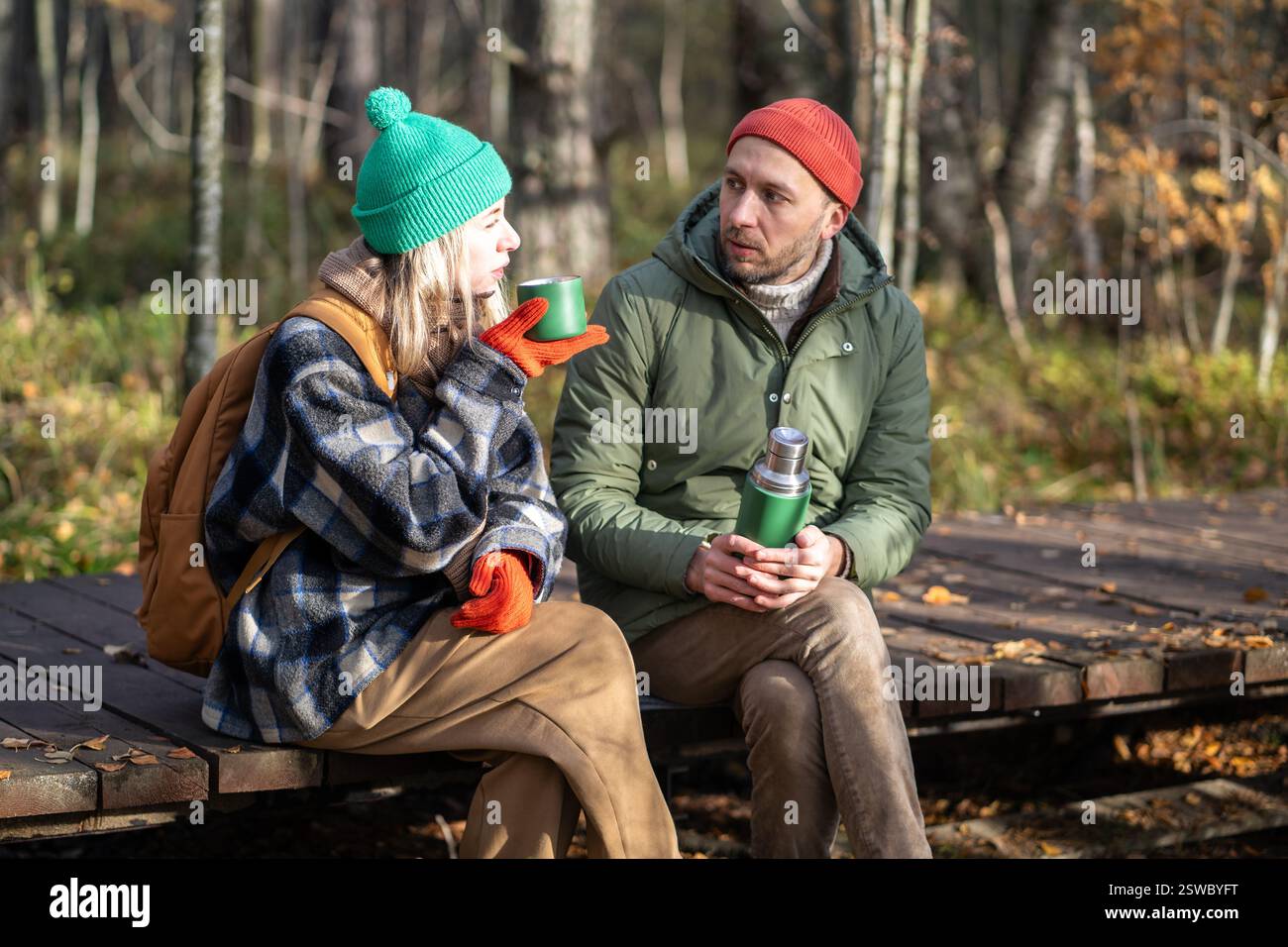 Homme détendu, femme se relaxant dans la forêt d'automne, boire du thé, communiquer, passer un bon moment tranquille ensemble Banque D'Images
