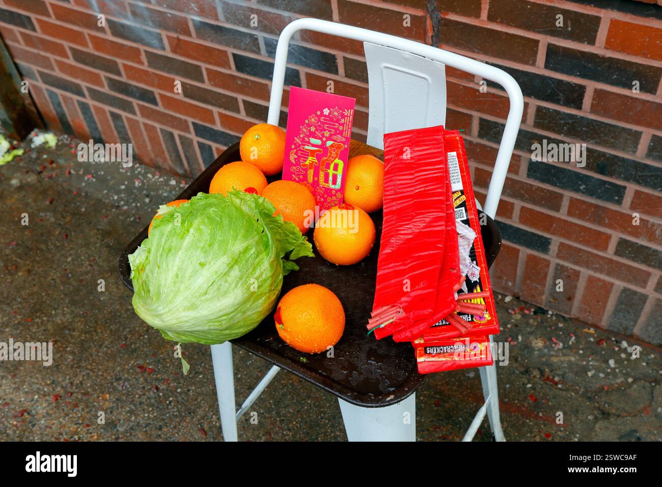 Une enveloppe rouge chanceuse, des oranges, de la laitue et des pétards en préparation pour une visite de danse du lion pendant le nouvel an chinois. Banque D'Images Une enveloppe rouge chanceuse, des oranges, de la laitue et des pétards en préparation pour une visite de danse du lion pendant le nouvel an chinois. Banque D'Images