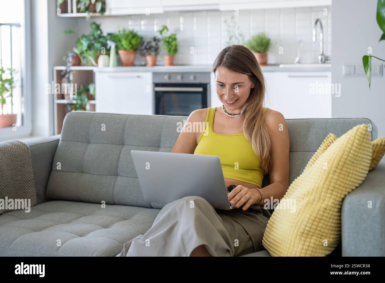 Femme souriante assis sur le canapé à la maison avec ordinateur portable souriant regardant l'écran recevoir de bonnes nouvelles dans le message. Banque D'Images