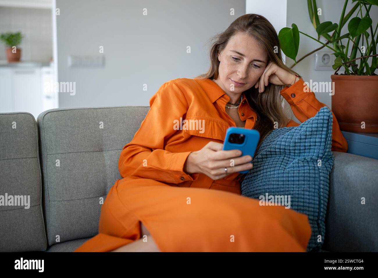 Femme focalisée calme utiliser un téléphone portable assis sur un canapé faisant des achats en ligne ou la livraison de la commande. Banque D'Images