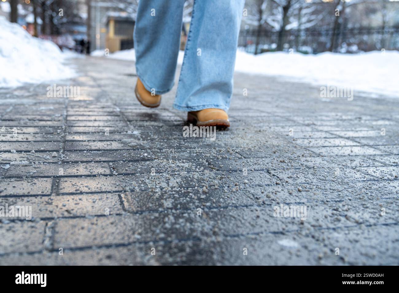 Produits chimiques antigivrage. Femme marchant dans la rue traitée avec du sel technique ou des produits chimiques de dégivrage Banque D'Images