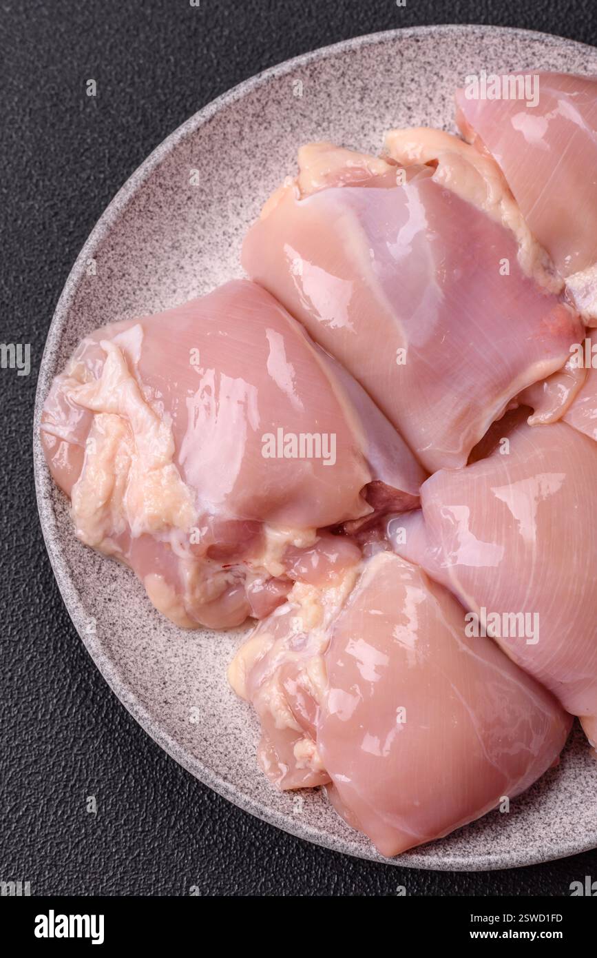 Filets de cuisse de poulet frais crus avec sel, épices et herbes Banque D'Images