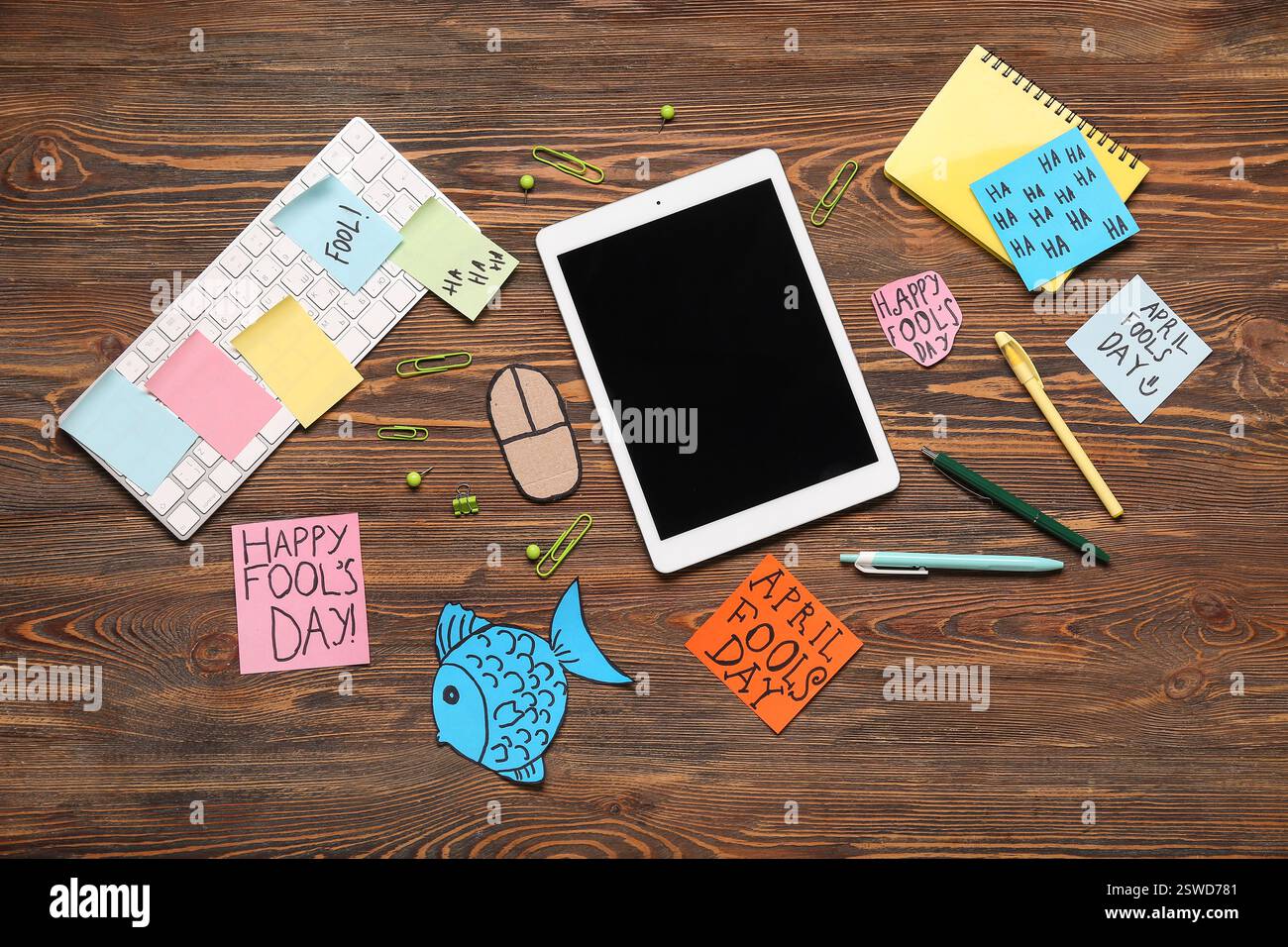 Tablette, clavier d'ordinateur, souris de carton et notes adhésives. Farce du jour des fous d'avril Banque D'Images